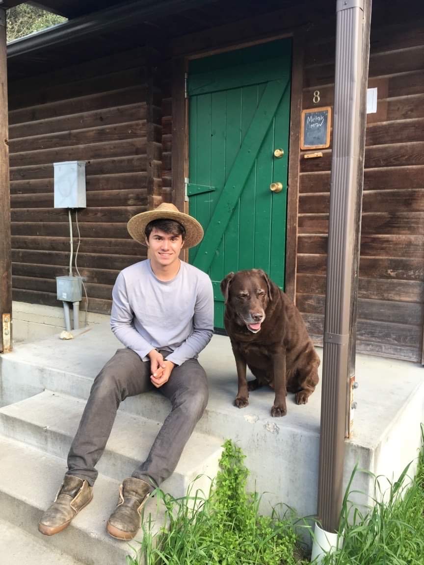 Duncan and chocolate lab Indy sit on cabin porch